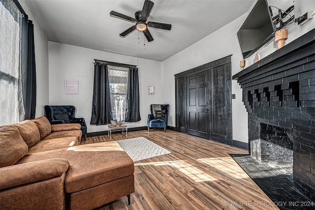 living room featuring hardwood / wood-style flooring, a brick fireplace, and ceiling fan