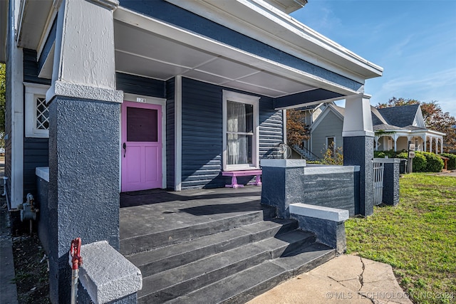 entrance to property with central AC, a yard, and a porch