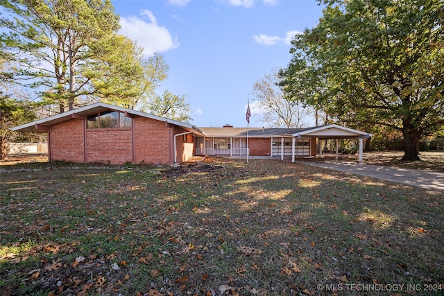 view of front of house with a carport, covered porch, and a front lawn