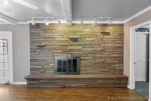 interior details with rail lighting, ornamental molding, ceiling fan, wood-type flooring, and a fireplace