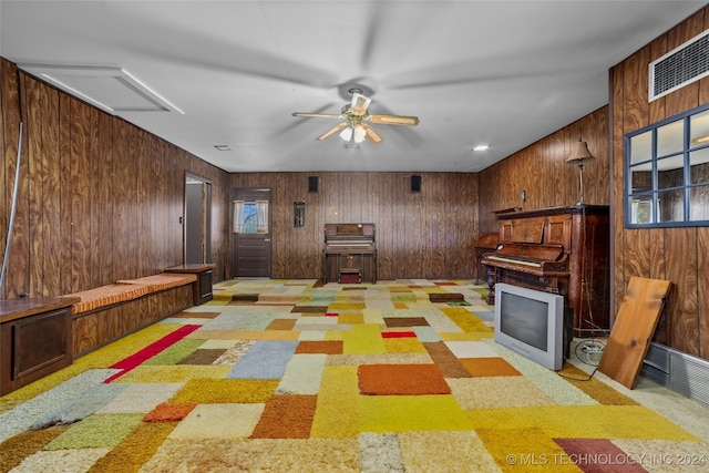 rec room featuring ceiling fan, light carpet, and wooden walls