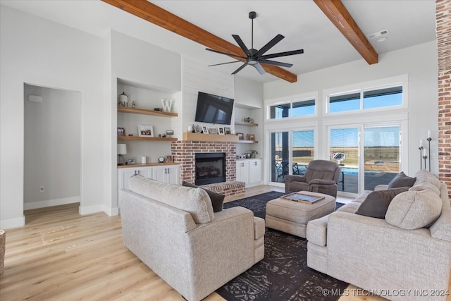 living room with ceiling fan, beam ceiling, built in features, a fireplace, and light hardwood / wood-style floors