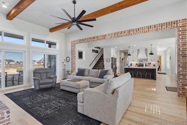 living room featuring beamed ceiling, a towering ceiling, light hardwood / wood-style flooring, and ceiling fan