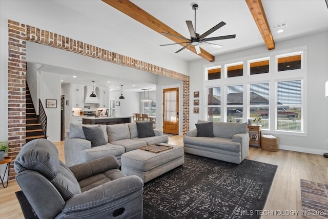 living room featuring beamed ceiling, light hardwood / wood-style flooring, and ceiling fan