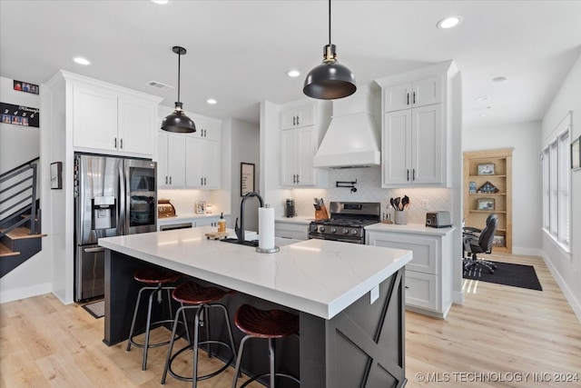 kitchen featuring white cabinets, custom exhaust hood, a center island with sink, and stainless steel appliances