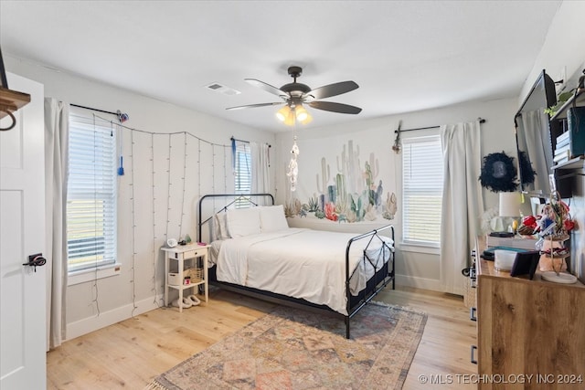 bedroom with light hardwood / wood-style floors, multiple windows, and ceiling fan