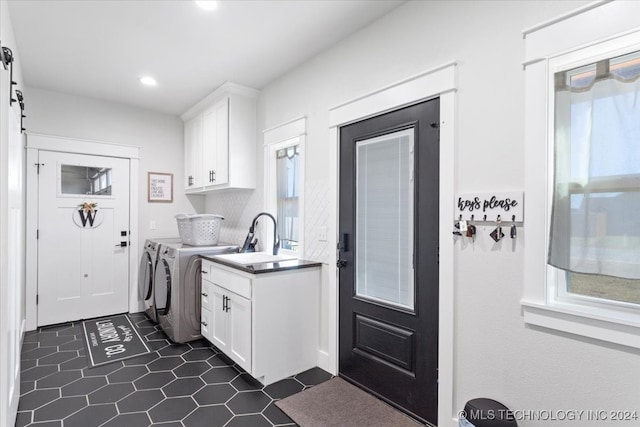 laundry area with washer and dryer, cabinets, dark tile patterned floors, and sink