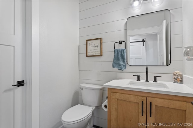 bathroom with wooden walls, vanity, and toilet