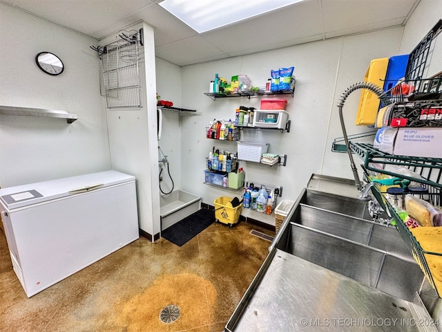 kitchen featuring stainless steel counters, concrete floors, and fridge