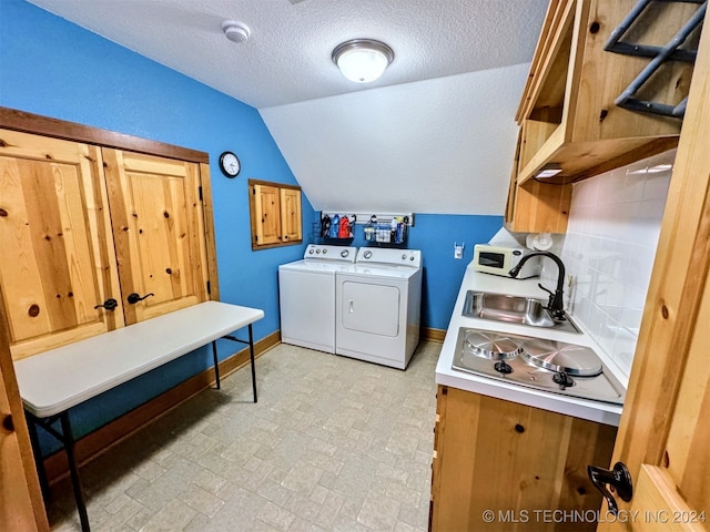 clothes washing area featuring washer and clothes dryer, a textured ceiling, and sink