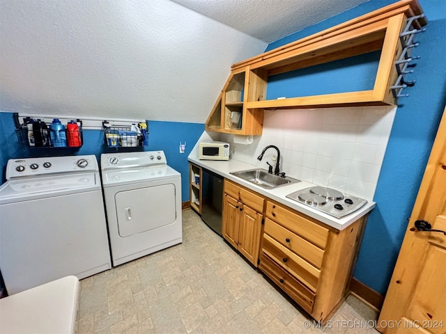 laundry area with a textured ceiling, washing machine and dryer, and sink