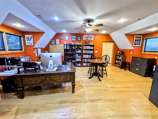 home office with ceiling fan, light hardwood / wood-style floors, a textured ceiling, and vaulted ceiling