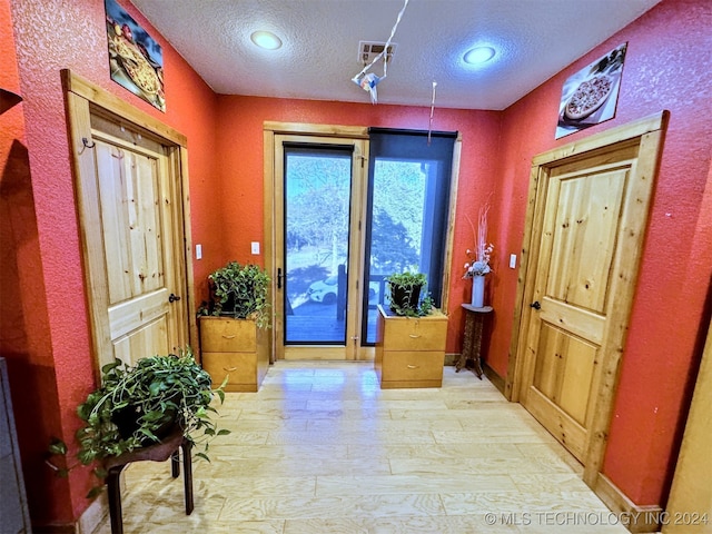 entryway featuring light hardwood / wood-style flooring and a textured ceiling