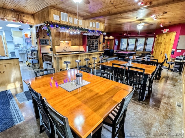 dining area featuring ceiling fan, sink, wooden ceiling, and concrete floors