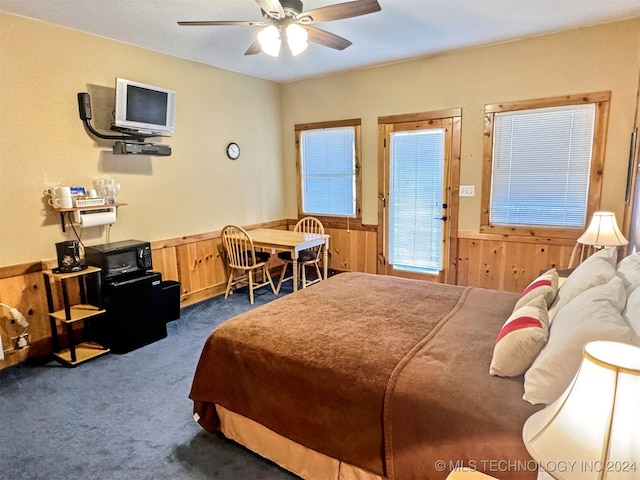 carpeted bedroom with wooden walls and ceiling fan