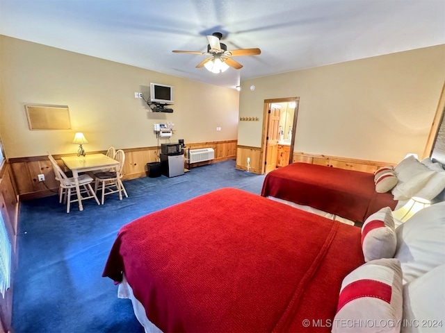 carpeted bedroom with ceiling fan, radiator heating unit, and wooden walls