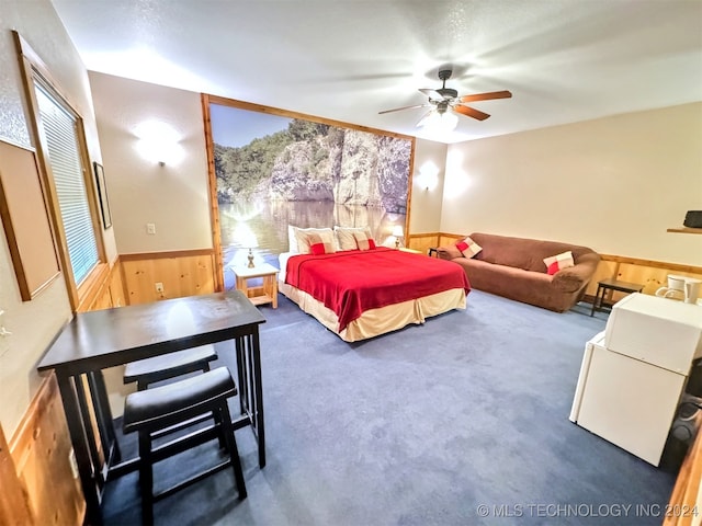 bedroom with wooden walls, ceiling fan, and dark colored carpet