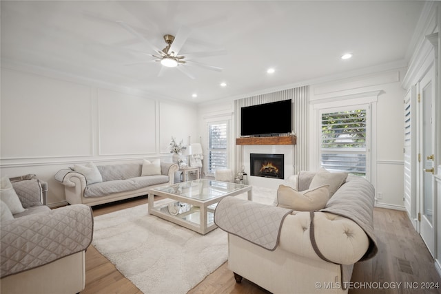 living room with light wood-type flooring, ceiling fan, and ornamental molding