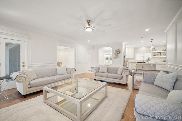 living room with hardwood / wood-style flooring, ceiling fan, crown molding, and sink