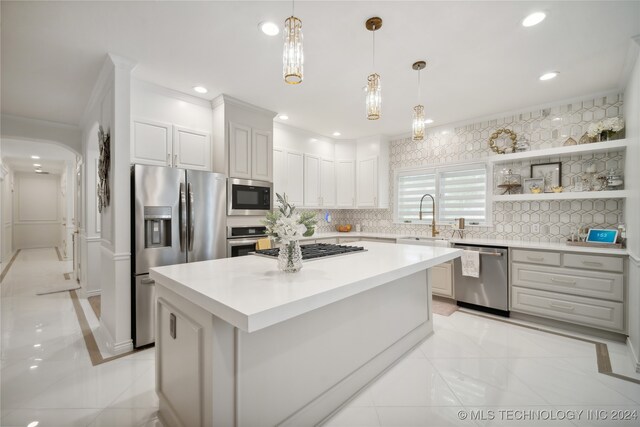 kitchen with ornamental molding, stainless steel appliances, sink, a kitchen island, and hanging light fixtures