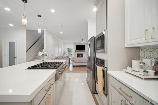 kitchen with backsplash, stainless steel appliances, decorative light fixtures, white cabinetry, and light tile patterned flooring