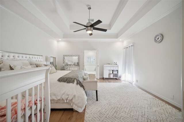 bedroom with hardwood / wood-style floors, ceiling fan, crown molding, and a tray ceiling