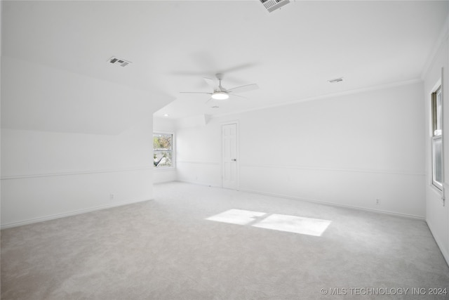 unfurnished room featuring light carpet, crown molding, ceiling fan, and lofted ceiling