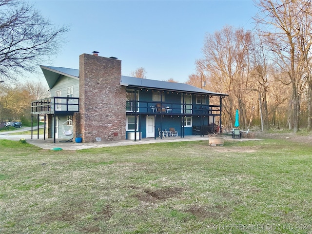 rear view of house featuring a patio area, a yard, and a balcony