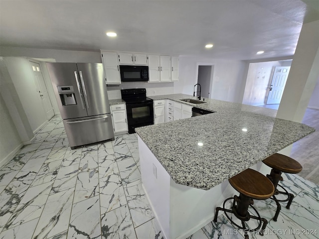 kitchen with black appliances, white cabinets, sink, a kitchen bar, and kitchen peninsula