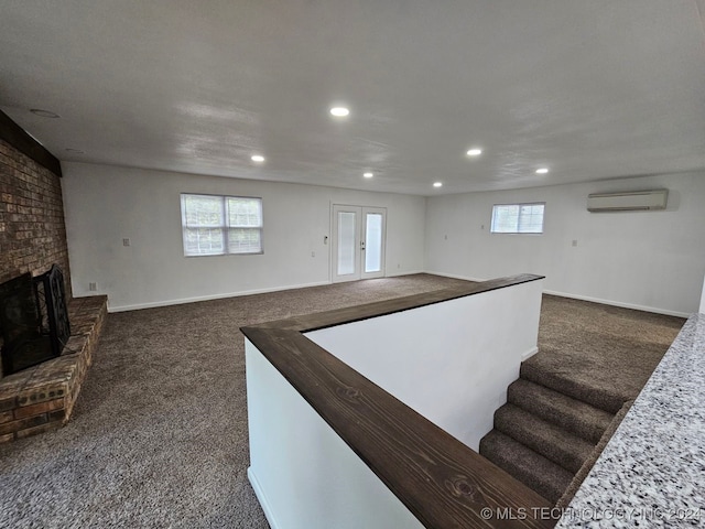 interior space with a wall unit AC, carpet flooring, french doors, and a brick fireplace