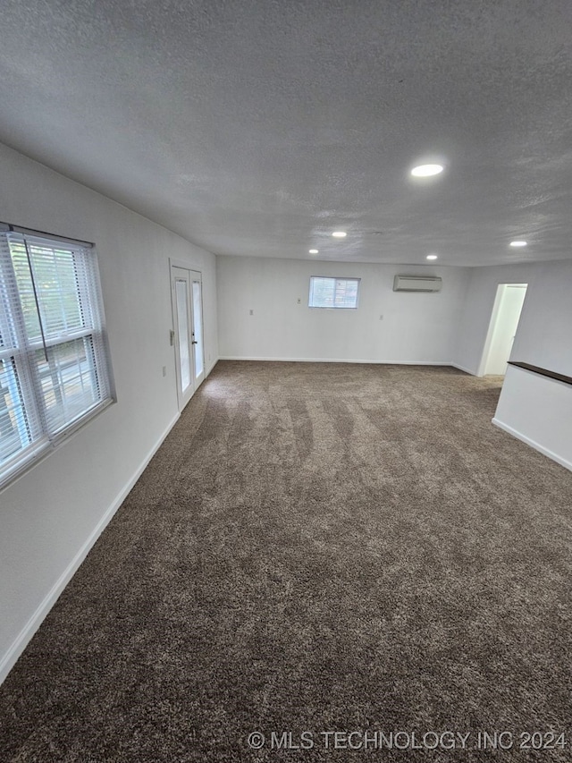 empty room with an AC wall unit, carpet, and a textured ceiling