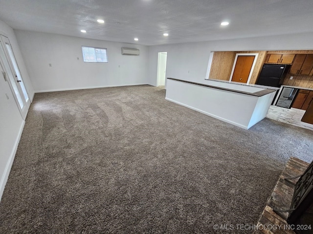 unfurnished living room featuring a wall mounted air conditioner, a textured ceiling, and dark colored carpet