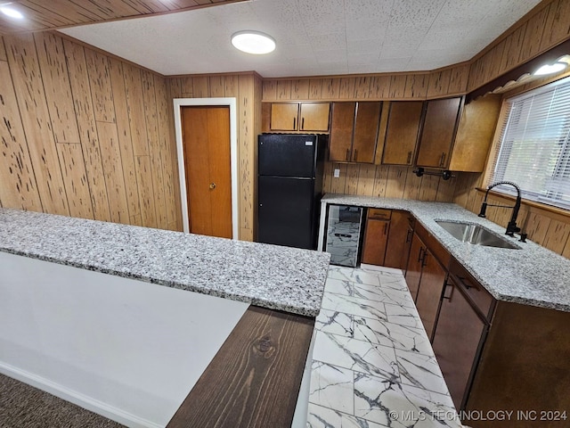 kitchen with wine cooler, black fridge, wooden walls, and sink