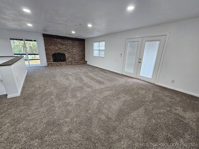 unfurnished living room with carpet flooring, french doors, and a brick fireplace