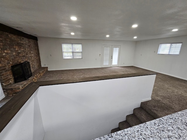 stairs with carpet flooring, a textured ceiling, and a brick fireplace