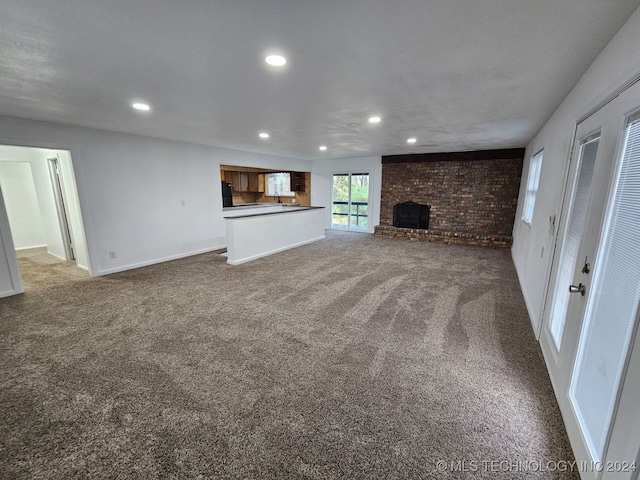 unfurnished living room with a fireplace, carpet floors, and brick wall