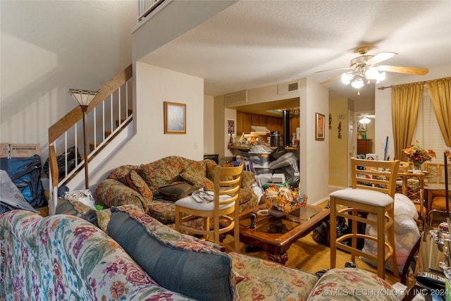 living room featuring ceiling fan and a textured ceiling