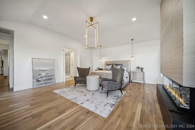 bedroom with hardwood / wood-style flooring, a multi sided fireplace, and lofted ceiling