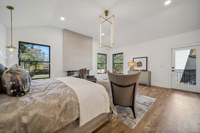 bedroom with access to exterior, light wood-type flooring, vaulted ceiling, and multiple windows