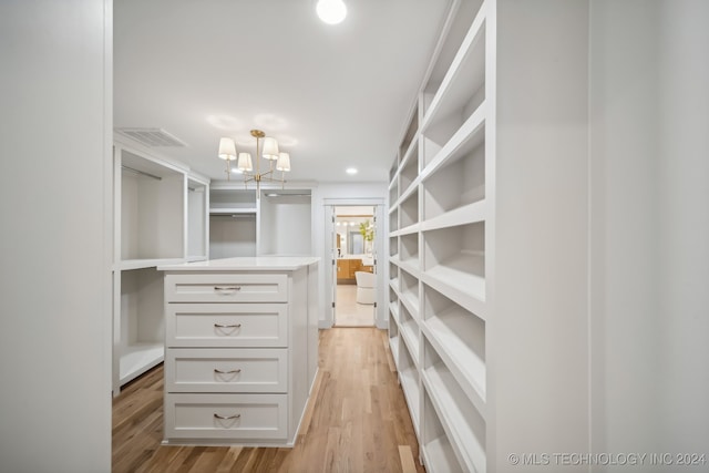 spacious closet featuring a chandelier and light hardwood / wood-style floors