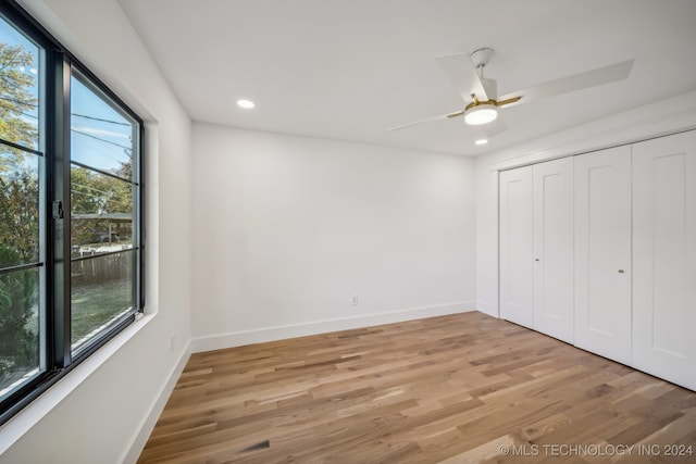 unfurnished bedroom featuring a closet, multiple windows, ceiling fan, and light hardwood / wood-style flooring