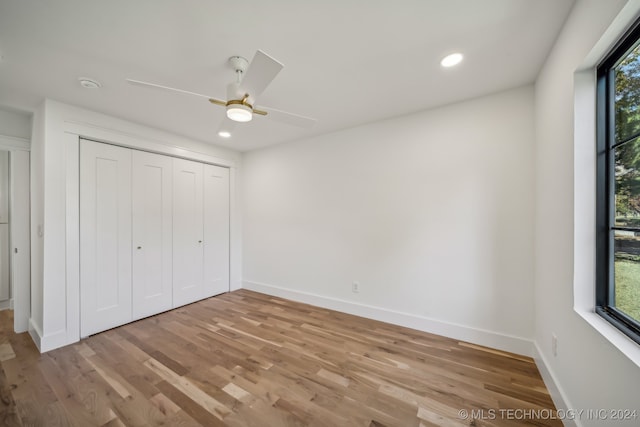 unfurnished bedroom featuring light wood-type flooring, multiple windows, and ceiling fan