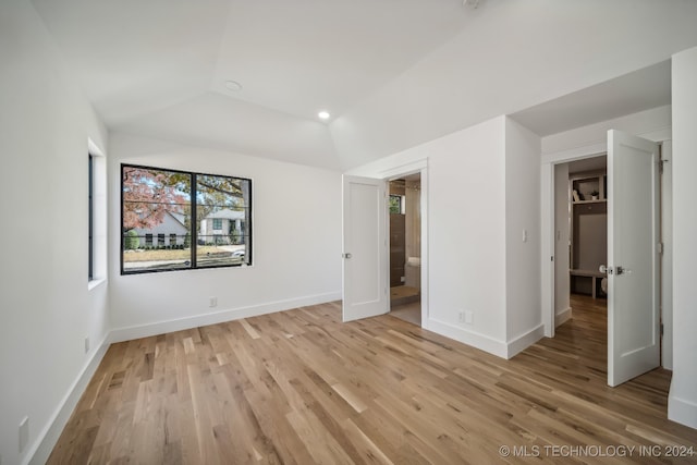 unfurnished bedroom featuring light wood-type flooring and lofted ceiling