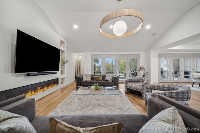 living room with french doors, high vaulted ceiling, and light hardwood / wood-style flooring