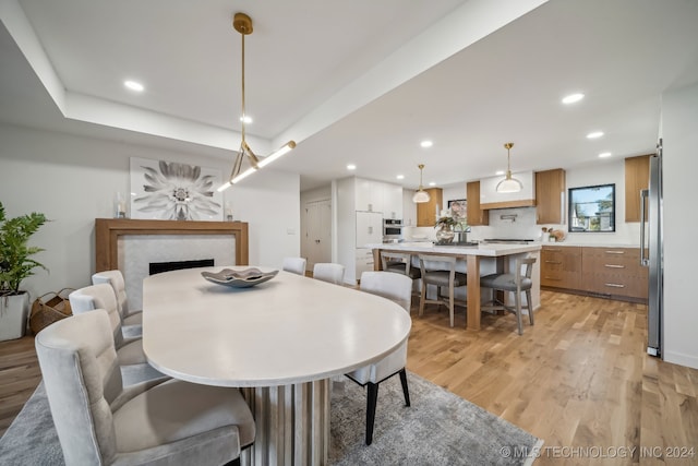 dining space with a tray ceiling and light hardwood / wood-style flooring