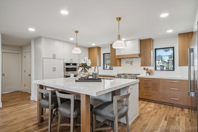 kitchen featuring a wealth of natural light, light hardwood / wood-style flooring, white cabinets, and decorative light fixtures