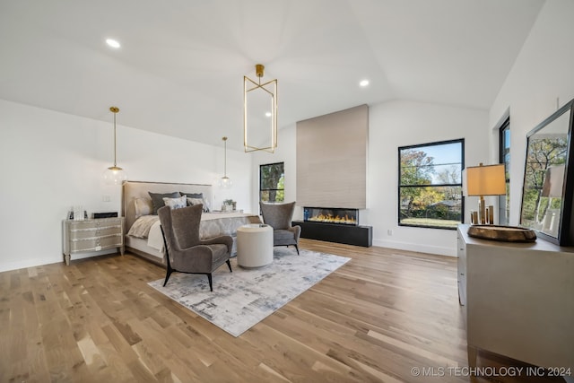 bedroom with a large fireplace, light hardwood / wood-style floors, and lofted ceiling