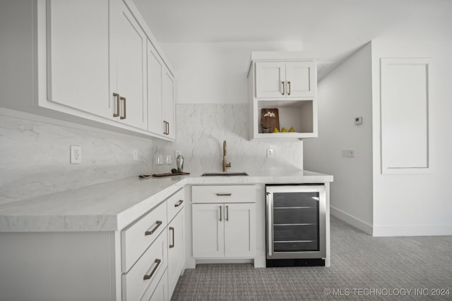 kitchen with backsplash, light colored carpet, beverage cooler, sink, and white cabinets