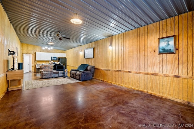 interior space with concrete flooring, wooden walls, ceiling fan, and lofted ceiling