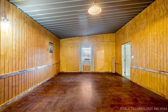 empty room with vaulted ceiling, cooling unit, and wooden walls